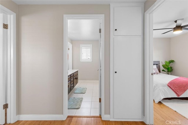 hall featuring light wood-style flooring and baseboards