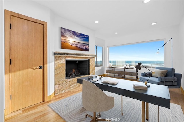 living area with baseboards, a high end fireplace, light wood-style flooring, and recessed lighting