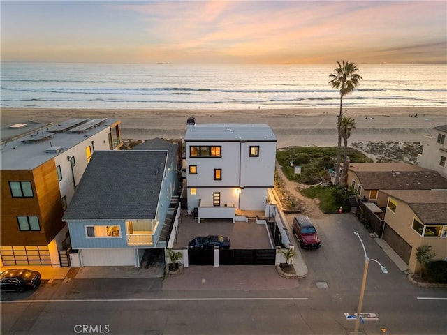 aerial view at dusk featuring a beach view and a water view