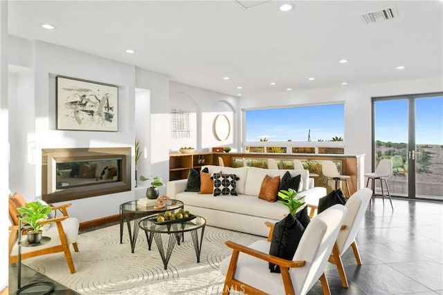 living area with recessed lighting, visible vents, and a glass covered fireplace