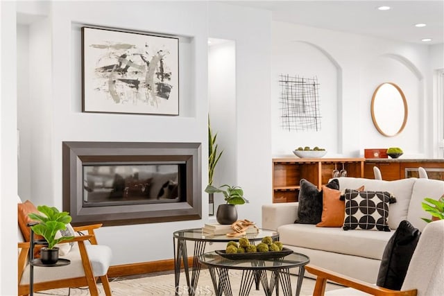 sitting room with baseboards, wood finished floors, a glass covered fireplace, and recessed lighting