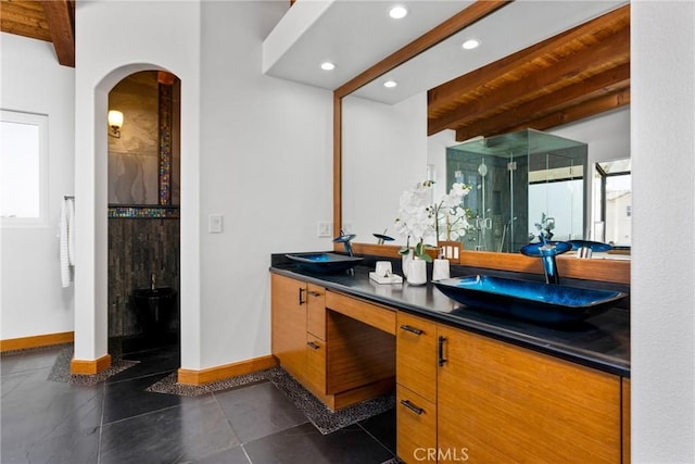 bathroom with a stall shower, a sink, beam ceiling, and baseboards