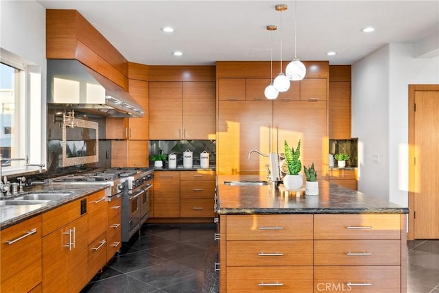 kitchen with brown cabinetry, double oven range, a sink, and decorative backsplash