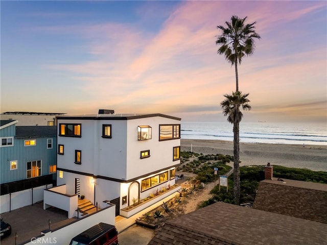 view of front of house featuring a view of the beach, a water view, and stucco siding