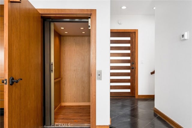 hallway with recessed lighting, elevator, and baseboards