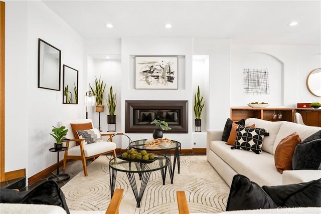 living room featuring a glass covered fireplace, baseboards, and recessed lighting