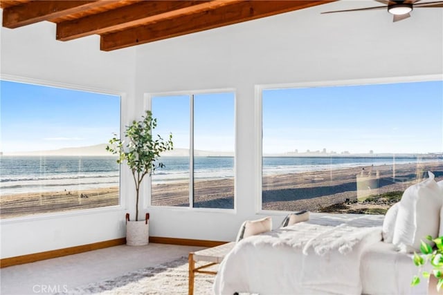 bedroom featuring carpet, a view of the beach, a water view, beamed ceiling, and baseboards