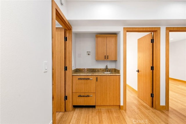 interior space with a sink, light wood-style flooring, and baseboards