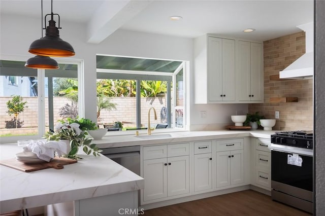 kitchen featuring tasteful backsplash, light stone counters, wood finished floors, gas stove, and a sink