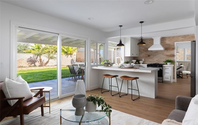 kitchen featuring a breakfast bar area, light countertops, a peninsula, custom exhaust hood, and stainless steel appliances