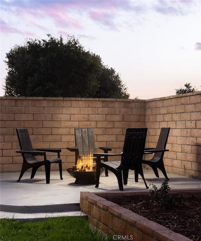 patio terrace at dusk featuring an outdoor fire pit