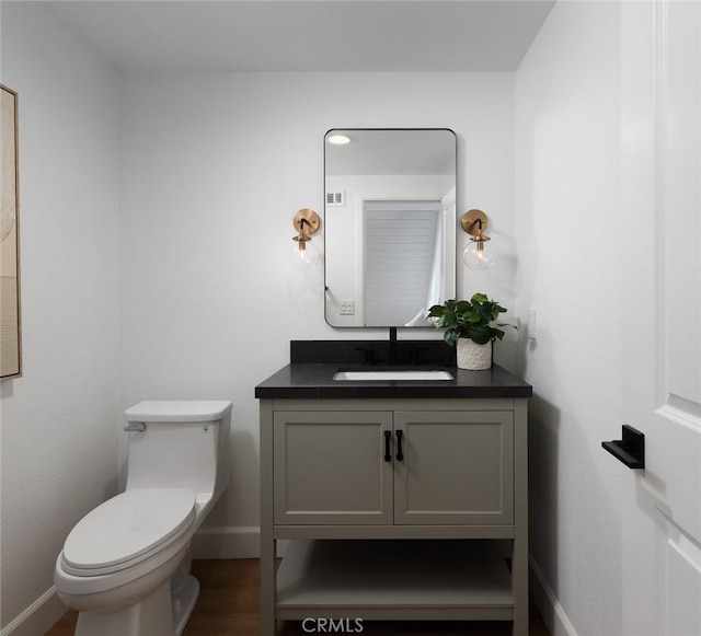 bathroom with baseboards, toilet, wood finished floors, and vanity