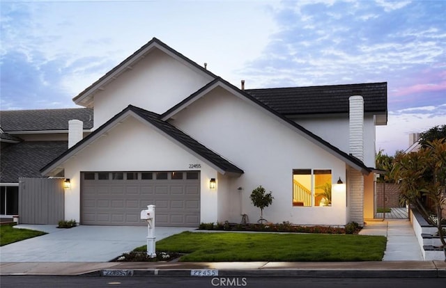 view of front facade featuring a front yard, a gate, an attached garage, stucco siding, and concrete driveway