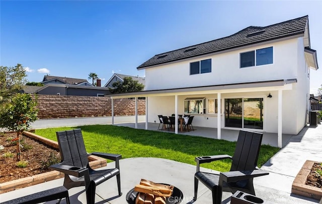 back of house featuring a patio area, stucco siding, a yard, and fence