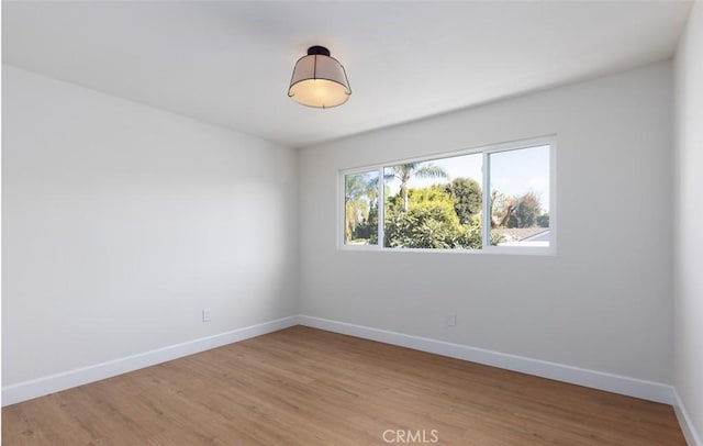 empty room featuring baseboards and light wood-type flooring