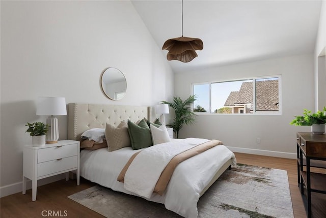 bedroom featuring lofted ceiling, wood finished floors, and baseboards