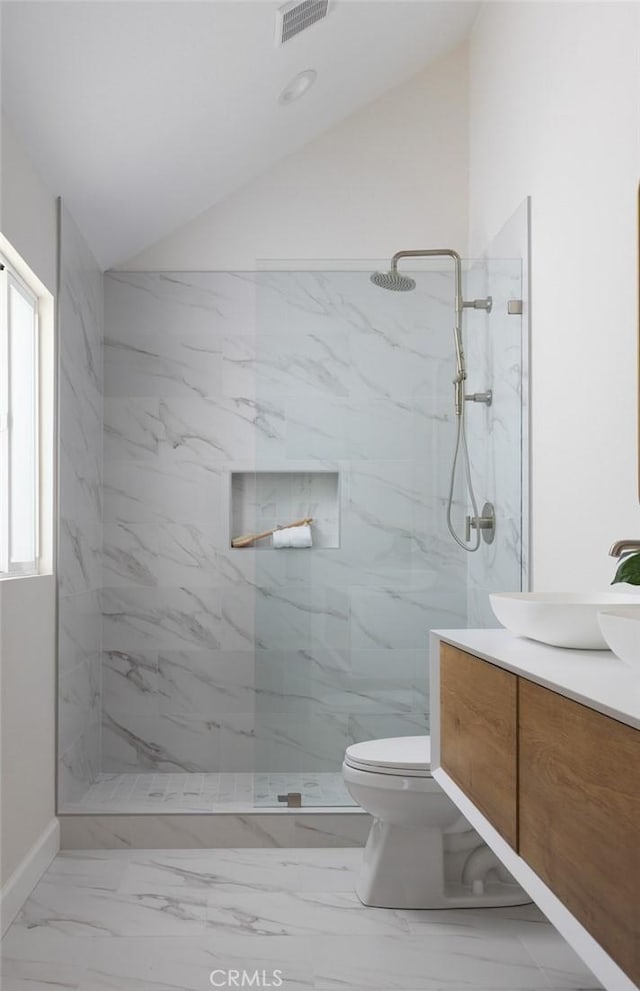 full bath featuring a marble finish shower, toilet, lofted ceiling, marble finish floor, and vanity