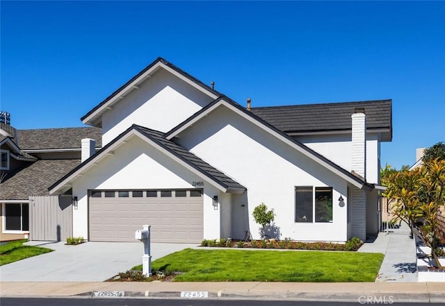 view of front of house with stucco siding, concrete driveway, a front yard, a garage, and a chimney