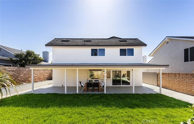 back of house featuring a yard, fence, stucco siding, and a patio area