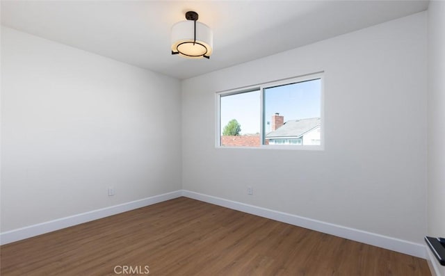 spare room featuring baseboards and wood finished floors