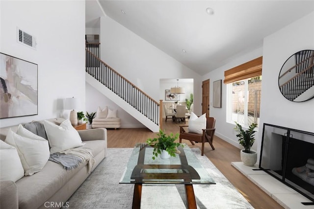 living area featuring stairway, wood finished floors, visible vents, and high vaulted ceiling