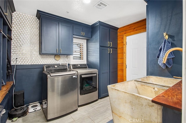 clothes washing area with cabinet space, washing machine and dryer, and visible vents