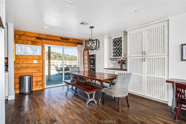 dining room with dark wood-style floors, visible vents, a notable chandelier, and a textured ceiling