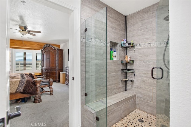 bathroom featuring a stall shower, ceiling fan, and a textured ceiling