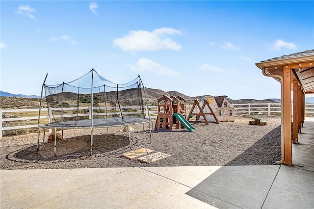 communal playground with a trampoline, fence, and a mountain view