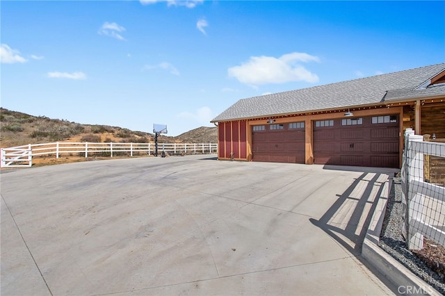 view of property exterior featuring a garage, fence, and roof with shingles