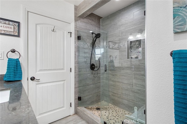 full bathroom featuring a stall shower, beam ceiling, and a sink