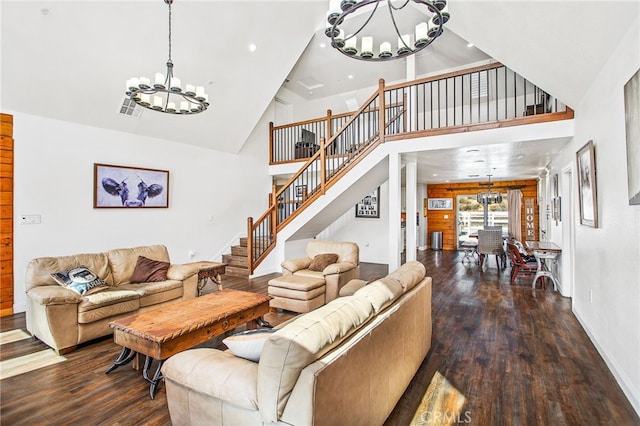 living area with a chandelier, high vaulted ceiling, wood finished floors, visible vents, and stairs