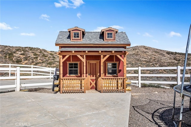 view of outdoor structure featuring an outbuilding, a mountain view, and fence