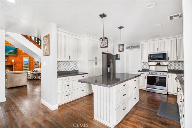 33210 Crown Valley Rd, Temecula, CA 92592 - kitchen featuring stainless steel appliances, backsplash, white cabinetry, dark wood-type flooring, and a kitchen island