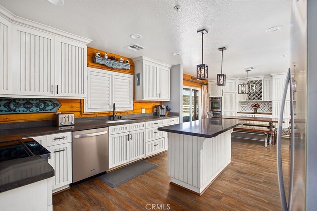33210 Crown Valley Rd, Temecula, CA 92592 - kitchen featuring stainless steel appliances, a sink, dark countertops, dark wood-style floors, and a kitchen island