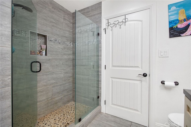 bathroom with toilet, a stall shower, and vanity