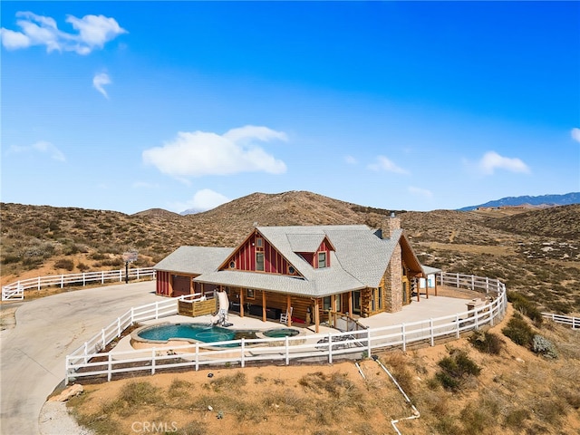 rear view of property with an exterior structure, a mountain view, and a chimney