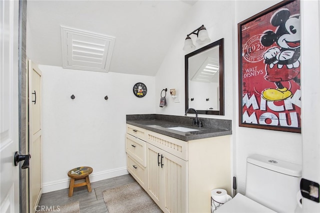 bathroom featuring toilet, wood finished floors, vanity, and baseboards