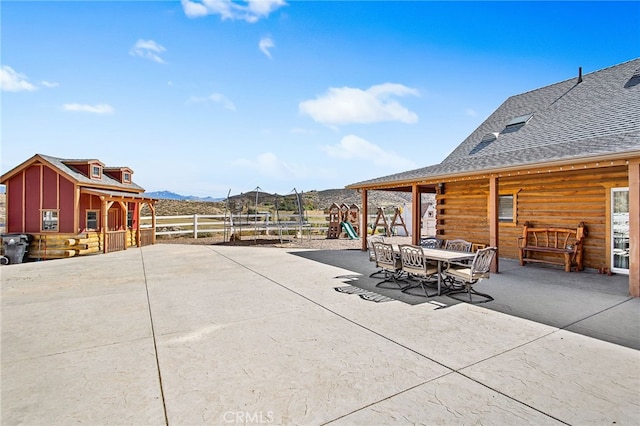 view of patio with fence, a mountain view, and outdoor dining area