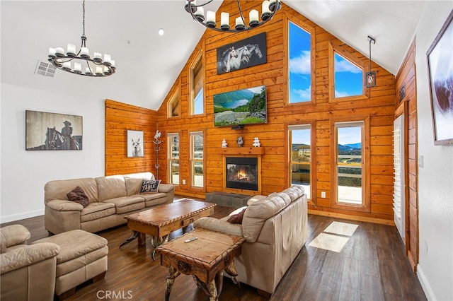 living area featuring dark wood-style flooring, wood walls, visible vents, and a notable chandelier