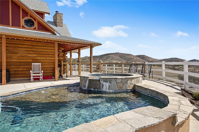 view of swimming pool featuring a pool with connected hot tub and a mountain view