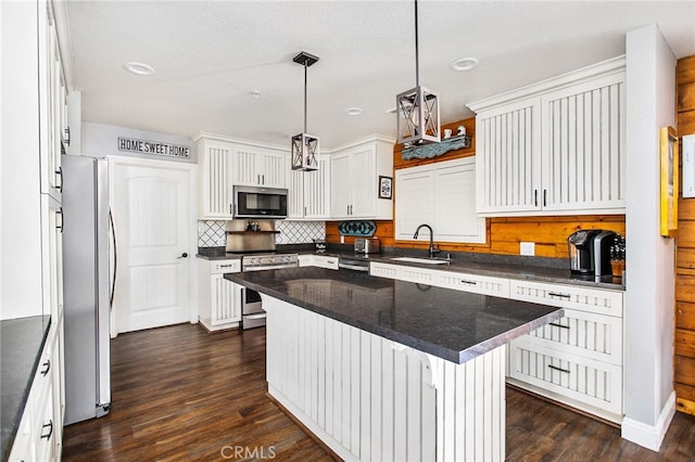 kitchen with stainless steel appliances, dark wood-type flooring, a sink, white cabinetry, and decorative backsplash