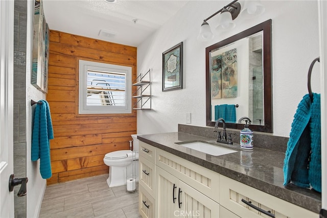 bathroom featuring wood walls, vanity, toilet, and walk in shower