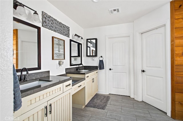 kitchen featuring dark stone countertops, visible vents, and a sink