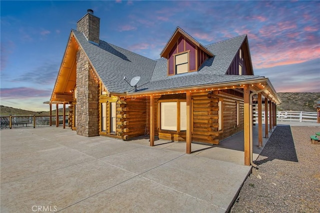 33210 Crown Valley Rd, Temecula, CA 92592 - back of property at dusk with log siding, a patio area, fence, and roof with shingles