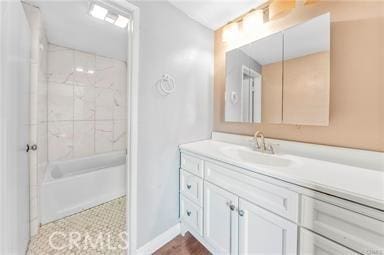 bathroom with baseboards, shower / bathing tub combination, and vanity