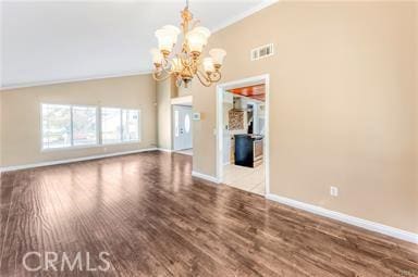 unfurnished living room with a notable chandelier, wood finished floors, visible vents, and baseboards