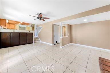 unfurnished living room featuring light tile patterned floors, ceiling fan, stairs, and baseboards