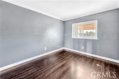 unfurnished room featuring ornamental molding, wood finished floors, and baseboards