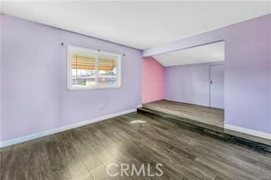 interior space featuring vaulted ceiling with beams, wood finished floors, and baseboards